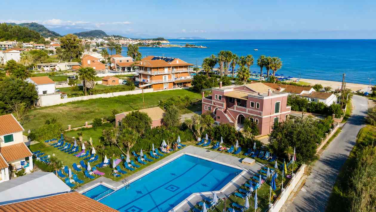 Monika Hotel pool at golden hour, surrounded by whitewashed walls, palm trees and bougainvillea in Sidari, Corfu